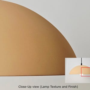 May include: Close-up view of a light brown, semi-circular lamp shade with a textured finish. The lamp is suspended from a black cord against a white background. The image also includes a smaller inset image of the lamp.