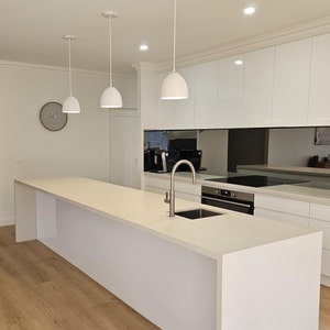 Three white dome pendant lights over the modern kitchen island as statement lighting