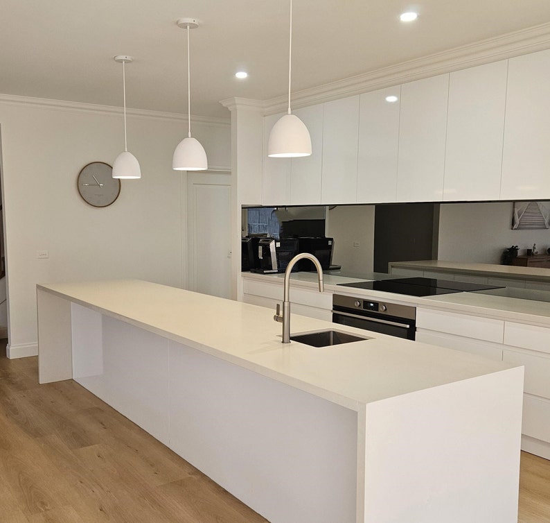 Three white dome pendant lights over the modern kitchen island as statement lighting