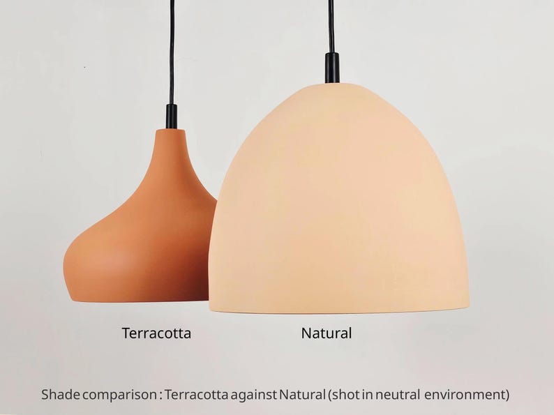 May include: Two pendant lights, one terracotta and one natural, hang from black cords. The terracotta light has a teardrop shape, while the natural light is a rounded dome. The text below reads "Terracotta" and "Natural".