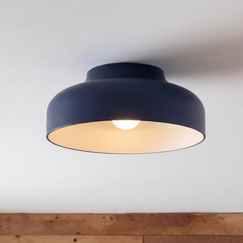A dark blue ceiling light fixture with a rounded shade and a bright light bulb. The interior of the shade is a light cream color. The fixture is mounted on a white ceiling.