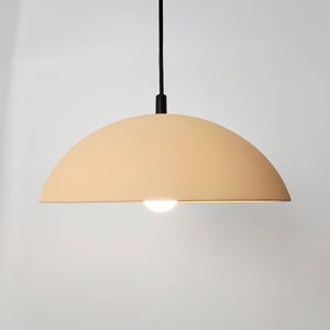 Elegant minimalist dome pendant in a soft, warm peach finish radiating a cozy, diffused downlight.