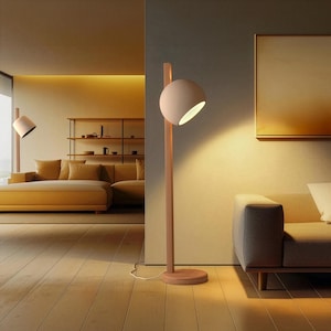 May include: A floor lamp featuring a tall, vertical wooden post attached to a circular wooden base. A spherical, matte beige lamp head is mounted near the top of the post, emitting a warm, focused light downward from its open side.
