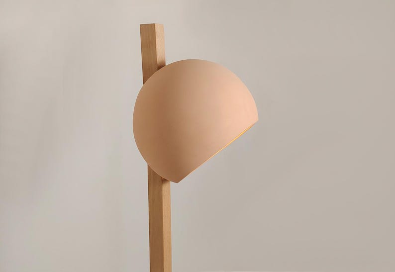 Add intrigue to your space with Naaya Stuck, a unique clay shade pierced by a wooden support
