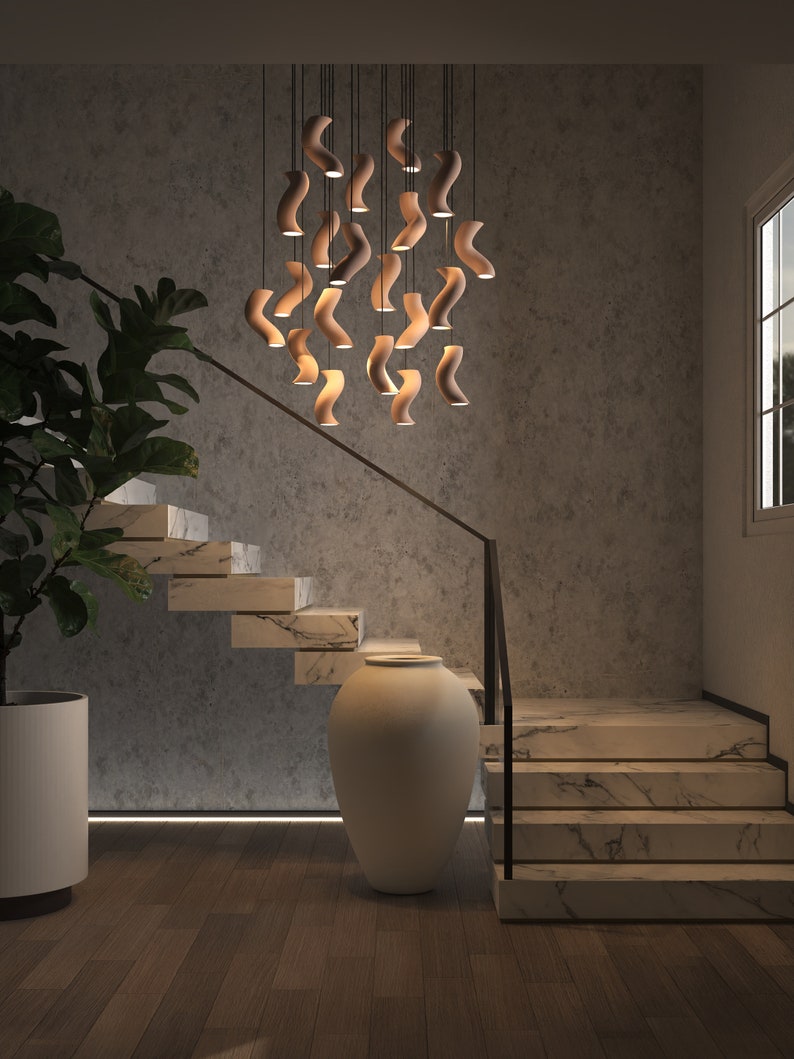 A stunning ceramic chandelier suspended elegantly in a two-story staircase, casting a luxurious warm glow, creating an inviting and opulent atmosphere
