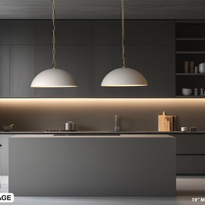 May include: A modern kitchen with dark gray cabinetry and a large island. Two milky white pendant lights hang above the island. The image includes a sink, stove, and shelving with kitchenware. The text in the image reads "19" Milky white x 2".