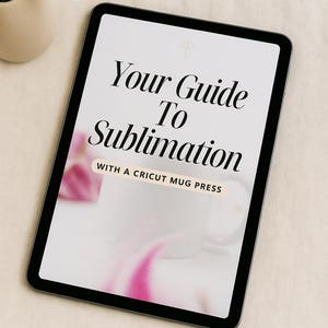 Könnte beinhalten: Ein digitales Tablet zeigt den Text "Your Guide To Sublimation" mit "WITH A CRICUT MUG PRESS" darunter. Die Worte "INSTANT DOWNLOAD" stehen unten. Auf dem Bildschirm ist eine weiße Tasse zu sehen. Im Hintergrund befindet sich eine kleine Vase mit weißen Blumen.
