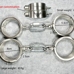Op de afbeelding: Twee paar zilveren metalen handboeien met een ketting die ze verbindt. Het grotere paar heeft een diameter van 6 inch en weegt 653 gram. Het kleinere paar heeft een diameter van 5,3 centimeter en weegt 603 gram. De handboeien hebben een lasergegraveerde inscriptie met de tekst "Good Boy".