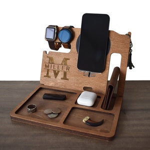 May include: Wooden phone stand with a wireless charging pad, two watch slots, a small tray, and a leather wallet holder. The stand is personalized with the initial "M" and the name "MILLER".
