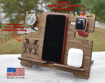 May include: Wooden phone stand with a personalized monogram, "M MILLER", and a cutout for an Apple Watch charger. The stand has a slot for a phone, a watch, and a small shelf for wireless earbuds. Made in the USA.