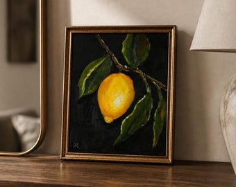 May include: A framed oil painting featuring a single bright yellow lemon hanging from a branch with several dark green leaves, set against a solid black background. The artwork is enclosed in a textured, metallic gold-toned frame.