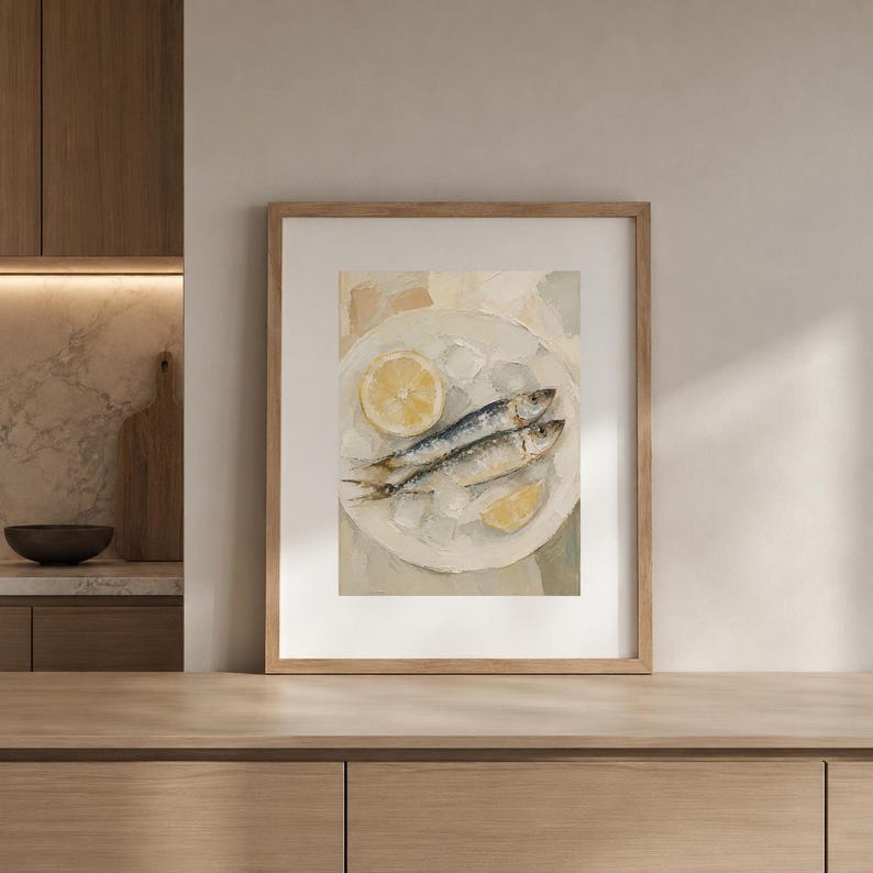May include: Framed art print of a still life featuring two sardines on a white plate with ice and lemon slices. The painting has a neutral color palette with a focus on the food. The artwork is displayed in a wooden frame.