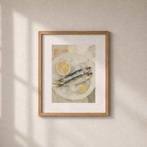 May include: A framed art print featuring a still life of two sardines on a white plate with lemon slices and ice. The painting has a neutral color palette with a focus on the food.