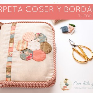 May include: A white fabric sewing case with a pink and white flower design. The case has a zipper closure and a pink and white striped trim. The case is sitting on a white surface with a pair of gold scissors and a spool of thread.