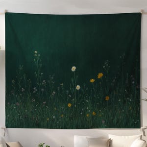 Könnte beinhalten: Ein dunkelgrünes Wandbehang mit einer Wiesenlandschaft mit weißen und gelben Wildblumen. Der Wandbehang hängt über einem weißen Sofa und einer Einrichtung in neutralen Tönen. Das Gesamtthema ist Natur und Wohnkultur.