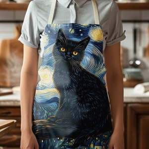 Könnte beinhalten: Eine schwarze Katze mit gelben Augen sitzt auf einem Ast vor einem sternenklaren Nachthimmel. Die Katze ist in einem stilisierten, malerischen Stil dargestellt, der an Vincent van Goghs "Sternennacht" erinnert. Die Schürze ist weiß mit einem schwarzen verstellbaren Band.