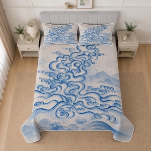 Könnte beinhalten: Eine gesteppte Tagesdecke und zwei passende Kissenbezüge mit einem blau-weißen Muster aus wirbelnden Wolken und Wellen. Das Bettwäsche-Set hat eine helle Grundfarbe mit einem sich wiederholenden Design aus stilisierten blauen Linien.