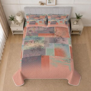 May include: A quilt and two matching pillow shams featuring a patchwork design of rectangular blocks in shades of coral, teal, and grey. The bedding set displays a subtle floral pattern overlaid on the geometric shapes with white piping edges.