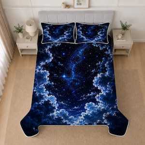 May include: A bedding set featuring a dark blue night sky pattern with a central galaxy, bright stars, and fluffy clouds. The set includes a large comforter and two matching rectangular pillowcases, all bordered with a thin white piping trim.