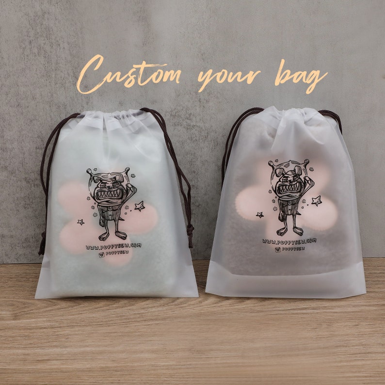 May include: Two white drawstring bags with black handles. Each bag has a cartoon illustration of a creature with a black outline. The text on the bag reads "www.puppyfeel.com @puppyfeel".