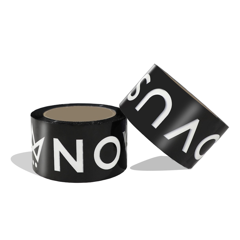 May include: Two rolls of black adhesive tape featuring bold white lettering. One roll is positioned upright, displaying the text NOVUS and a geometric crown icon, while the second roll is tilted, showing the letters OVUS in a clean, sans-serif font.