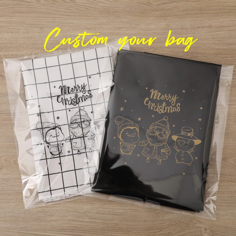 May include: Two Christmas gift bags in clear plastic. One is black with gold illustrations and text, the other white with black illustrations and text. The text reads "Merry Christmas" and "Custom your bag".