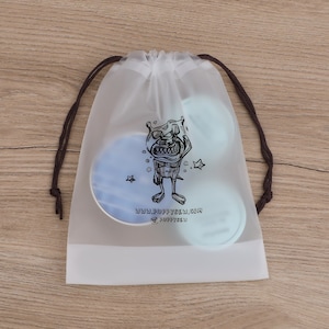 May include: A clear plastic drawstring bag with a black and white cartoon monster graphic. The bag has a brown drawstring and the text "www.puppysew.com @puppysew" printed on the front.