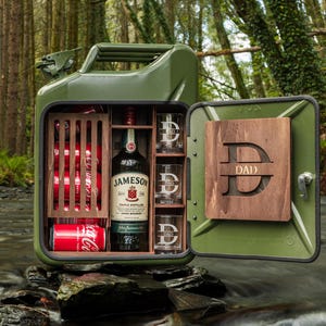 Peut inclure: Bar en jerricane métallique verte avec intérieur en bois. Contient une bouteille de whisky irlandais Jameson, des canettes de Coca-Cola et trois verres. La porte a un panneau en bois avec la lettre "D" et le mot "DAD".