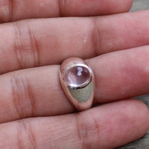 May include: A silver ring with a light pink oval gemstone.