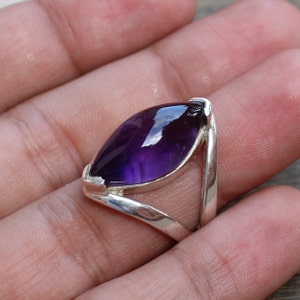 May include: A silver ring with a large, faceted, purple amethyst gemstone set in a unique, open design.