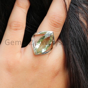 May include: A silver ring with a green gemstone set in a geometric design.