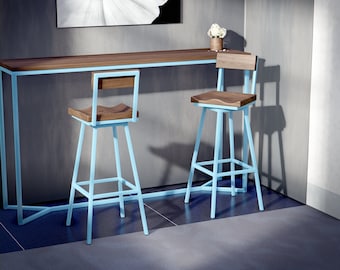 Puede incluir: Dos taburetes de bar con marcos de metal azul claro y asientos y respaldos de madera se colocan frente a una larga mesa de bar de madera con un marco azul claro a juego. Una impresión floral en blanco y negro cuelga de la pared.