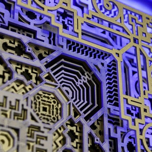 Pu&ograve; includere: Primo piano di un'opera d'arte geometrica a strati. Il design presenta intricati ritagli in tonalit&agrave; oro e grigio, con una luce blu che illumina lo sfondo. L'opera d'arte mostra un complesso motivo di forme e linee.