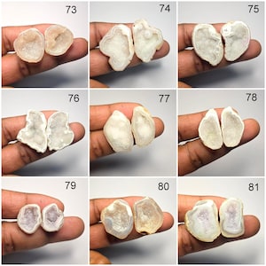 May include: A collection of nine pairs of geode halves, each held in a hand. The geodes vary in color, from white to light brown, with visible crystal formations inside. The image is well-lit, showcasing the natural textures and colors of the stones.