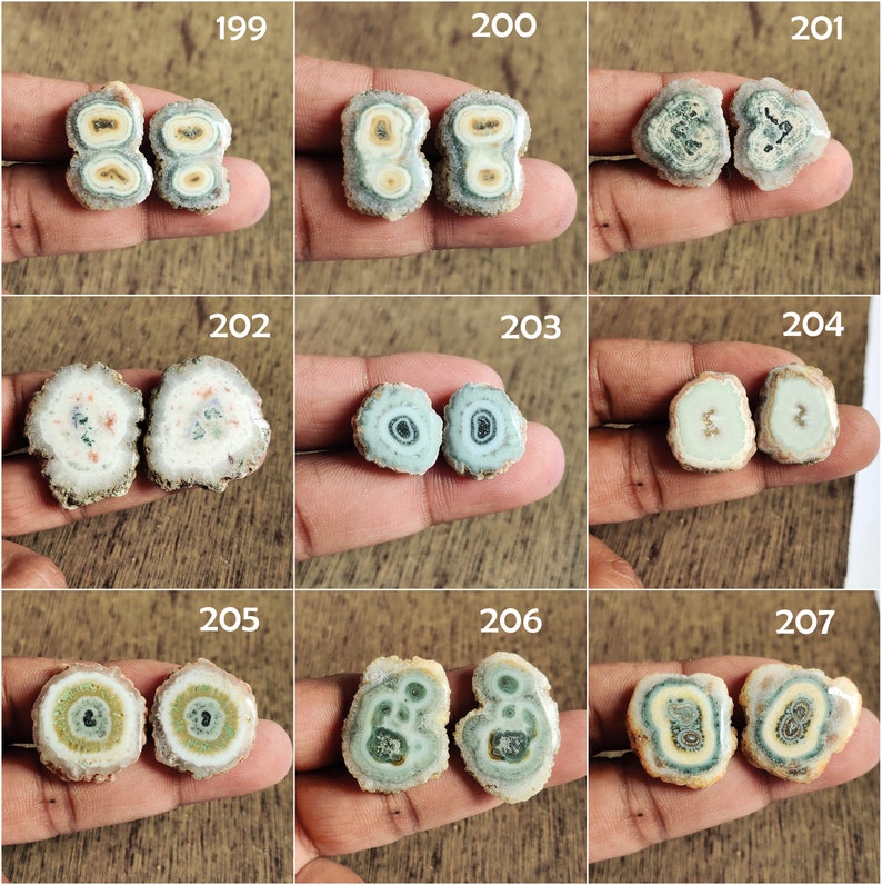 May include: Nine pairs of agate slices with different patterns and colors, including green, blue, white, and brown. The agate slices are arranged in a grid pattern on a wooden surface.