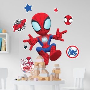 May include: A cartoon image of Spider-Man in a red and blue suit, with a large head and big eyes. The image includes several stickers of Spider-Man, stars, and the words "TWAIP" and "Spidey Amazing Fun". The character is posed on top of wooden blocks.