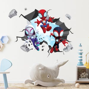 May include: A wall sticker showing three cartoon Spider-Man characters emerging from a cracked wall. The characters wear red, blue, and purple costumes. The background depicts a light blue sky.