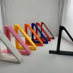 Peut inclure: Un ensemble de dix serre-livres en forme de triangle de différentes couleurs, dont le blanc, le rose, le jaune, le bleu, le rouge, l'orange et le noir. Les serre-livres sont en plastique et sont conçus pour maintenir les livres à la verticale.