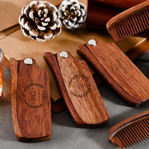 May include: Four wooden pocket combs with engraved designs. The combs are made of dark brown wood and have a folding design. The combs are engraved with the words "Tribute", "PG", "The", and "Attitude".