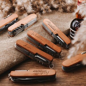 Peut inclure: Ensemble de couteaux de poche en bois personnalis&eacute;s avec des noms grav&eacute;s. Chaque couteau a un manche en bois brun et une lame argent&eacute;e. Les couteaux sont dispos&eacute;s sur une surface brune.