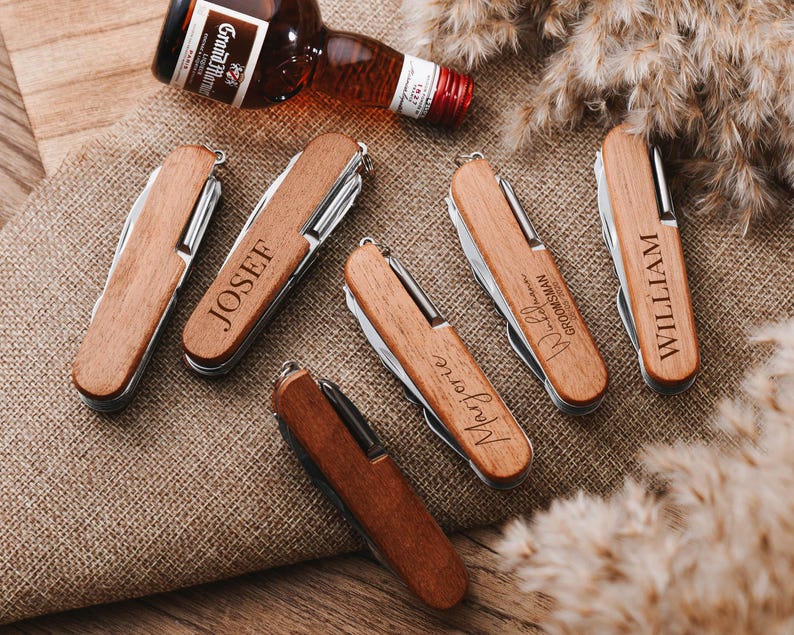 Peut inclure: Cinq couteaux de poche en bois avec des noms personnalis&eacute;s, dont "Josef", "William", "Mary Jo" et "Best Man, Groomsman". Les couteaux ont un manche en bois brun et des lames en m&eacute;tal argent&eacute;.