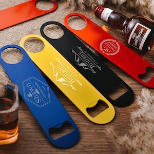 Könnte beinhalten: Fünf verschiedene farbige Flaschenöffner mit personalisierten Gravuren. Die Flaschenöffner sind aus Metall und haben ein klassisches Design. Die Gravuren beinhalten Namen und Sätze wie "Brittany", "Harley", "Shay" und "Groovy Granny 1941".