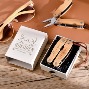 May include: A wooden multi-tool with a brown leather strap and the inscription "Hosoren best man". The multi-tool is in a white box with a black interior. The box has a logo that says "Hosoren Original Company" with a mountain and antlers.