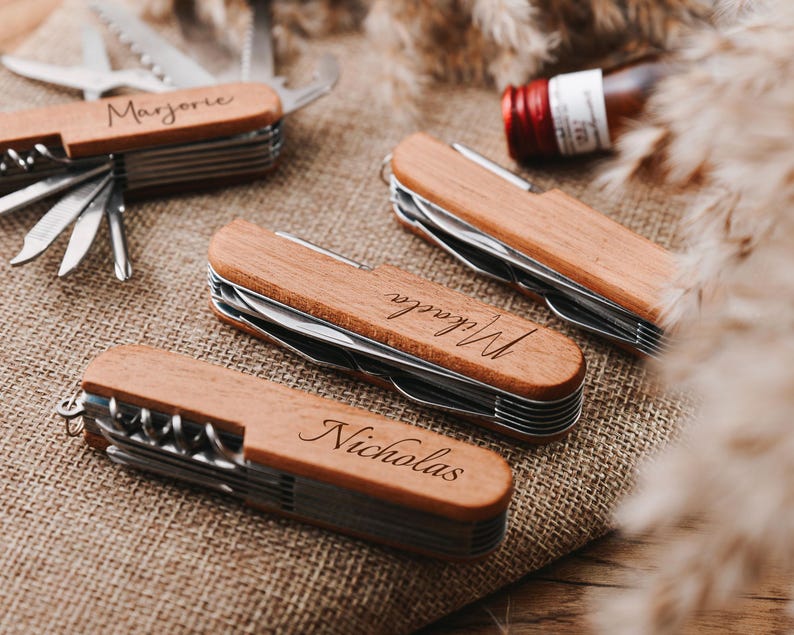 Peut inclure: Quatre couteaux de poche en bois personnalis&eacute;s avec des noms grav&eacute;s diff&eacute;rents. Les couteaux ont plusieurs outils, dont un ouvre-bouteille, une scie et un tournevis.