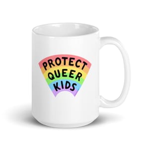 May include: White ceramic mug with a rainbow design and the text "PROTECT QUEER KIDS" in black.