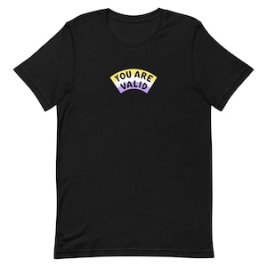 May include: Black t-shirt with a yellow, white, and purple arc design that says "You Are Valid" in black text.