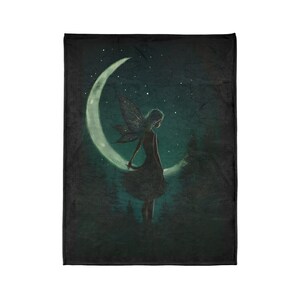 May include: A dark green and black throw blanket with a silhouette of a fairy with wings standing on a crescent moon. The fairy is facing to the right and the moon is glowing.