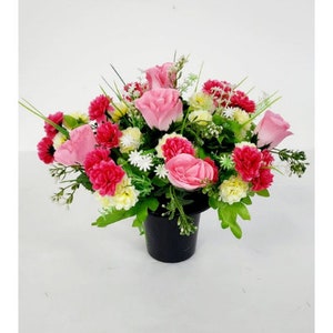 May include: A pink and white artificial flower arrangement in a black pot. The arrangement features roses and carnations.