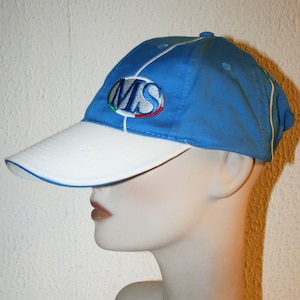 Op de afbeelding: Een blauwe en witte baseballpet met een witte klep en een witte streep in het midden. De pet heeft een geborduurd logo met de tekst "MS" in een blauwe ovaal met een rood-wit-groene streep.