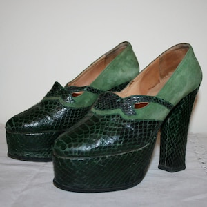 May include: A pair of green platform shoes with a snakeskin pattern. The shoes have a high heel and a thick platform.